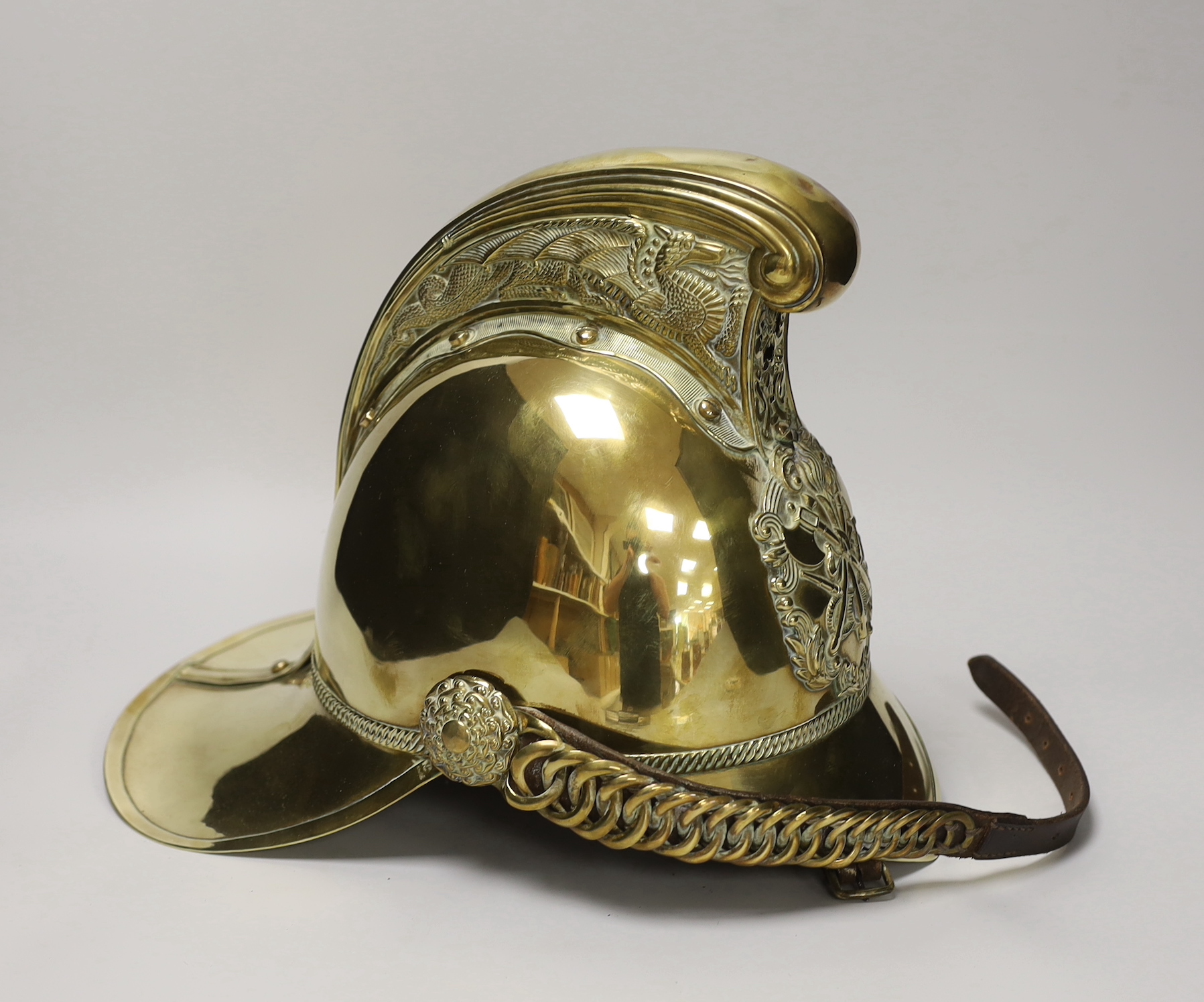 A late 19th/early 20th century brass Merryweather fire brigade helmet with embossed decoration and leather liner, 34cm in length